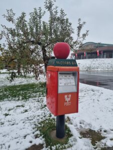 red letter box against snowy background with a red apple sculpture on top