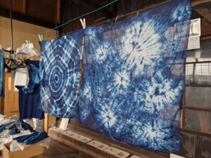 Two different styles of indigo dying shown hanging up to dry